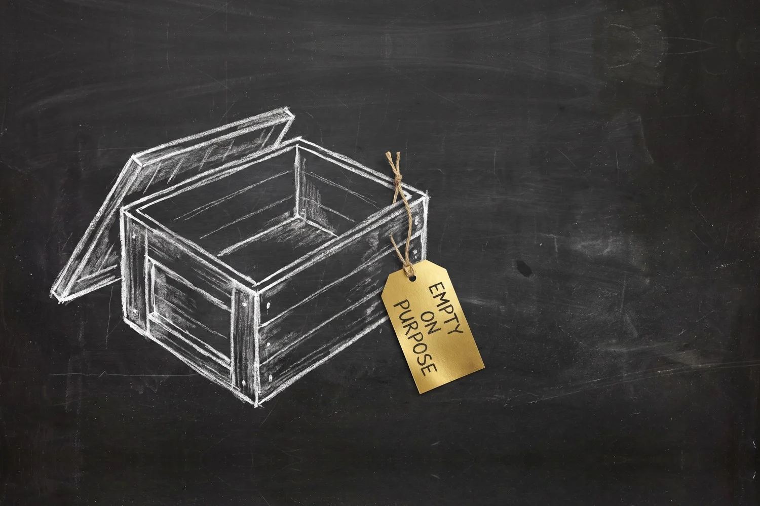 A chalkboard sketch: an open wooden crate with nothing inside it and a solid gold tag hanging from one corner reading EMPTY ON PURPOSE.